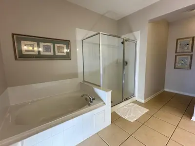 a bathroom with a tub and a glass shower at Vista Cay Jewel Luxury By Universal Orlando Rental in Orlando