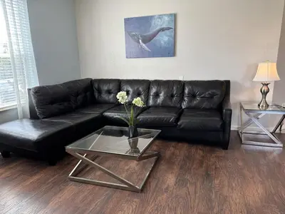 a living room with a black leather couch and two tables at Vista Cay Jewel Luxury By Universal Orlando Rental in Orlando