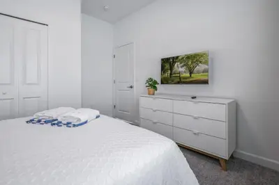 a white bedroom with a white bed and a dresser at Opulent Retreat Themed Bedrooms and Pool Paradise in Kissimmee