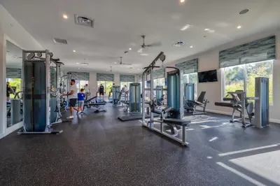 a gym with cardio equipment and people in the background at Opulent Retreat Themed Bedrooms and Pool Paradise in Kissimmee