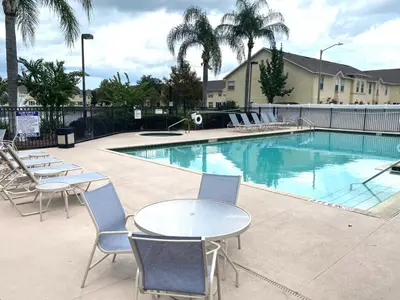 a swimming pool with tables and chairs and palm trees at Family Friendly Community in Kissimmee