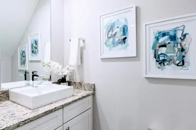 a bathroom with a white sink and paintings on the wall at Awesome 4 beds Villa 5 min to Disney in Orlando