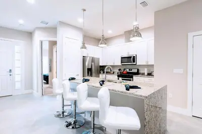 a kitchen with white cabinets and a counter with white chairs at Awesome 4 beds Villa 5 min to Disney in Orlando