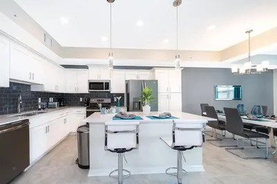 a kitchen with white cabinets and a table and chairs at Beautiful Apartments 5 Minutes away from Disney! in Kissimmee