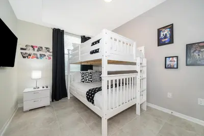a white bunk bed in a white room with a crib at Beautiful Apartments 5 Minutes away from Disney! in Kissimmee