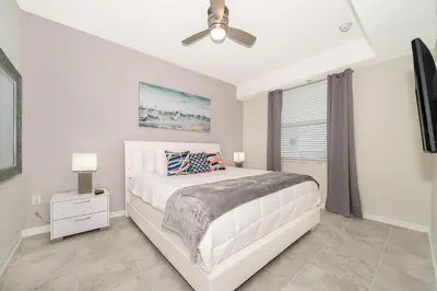 a white bedroom with a bed and a ceiling fan at Beautiful Apartments 5 Minutes away from Disney! in Kissimmee