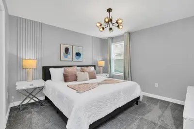 a white bedroom with a large bed and a chandelier at Luxury Incredible Themed Home best vacation in Kissimmee