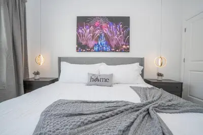 a bedroom with a bed with a grey blanket at Magnificient 4Bd w Pool @ Storey Lake Resort 2648 in Kissimmee