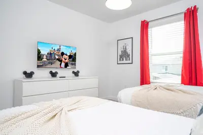 a white bedroom with two beds and a window at Magnificient 4Bd w Pool @ Storey Lake Resort 2648 in Kissimmee