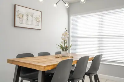 a dining room with a wooden table and chairs at Magical 5-Bedroom Retreat w/ Pool, 3 Ensuite Bedrooms, Near Disney, and Internet! in Kissimmee