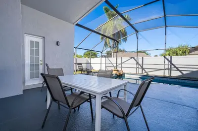 a dining room with a table and chairs and a pool at Magical 5-Bedroom Retreat w/ Pool, 3 Ensuite Bedrooms, Near Disney, and Internet! in Kissimmee