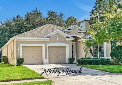 a house with a car garage in a yard at Windsor Hills 4BR's Mickeys Ranch Near Disney in Orlando