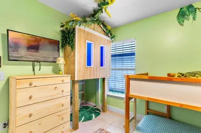 a bedroom with green walls and a wooden dresser at Beautiful Tropical Home with Private Heated and Chilled Pool in Kissimmee