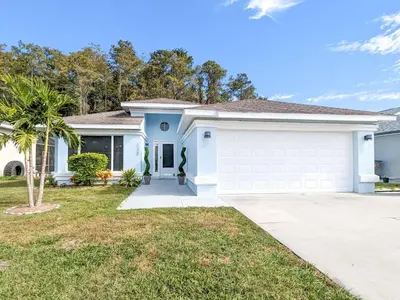 a white house with a garage at Beautiful Tropical Home with Private Heated and Chilled Pool in Kissimmee