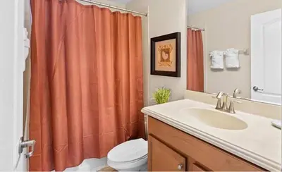 a bathroom with an orange shower curtain and a sink at 8931 Cuban Palm in Kissimmee