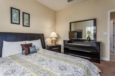a bedroom with a bed with a dresser and a piano at 3071 Beach Palm in Kissimmee
