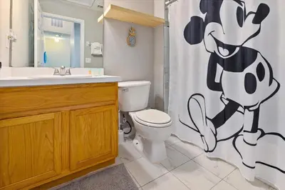 a bathroom with a toilet with a mickey mouse shower curtain at 8569 Crystal Cove in Kissimmee