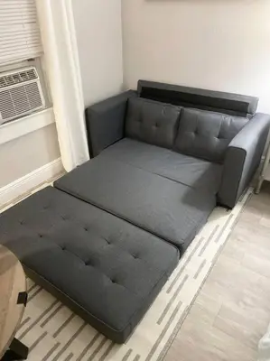 a futon bed in a room next to a window at 1 BD Apt close to Disney/Universal/Shopping/Dining in Kissimmee