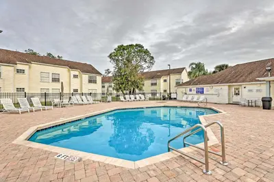 a swimming pool in a courtyard with chairs and a building at Kissimmee Condo with Perks 6 Mi to Disney World! in Kissimmee
