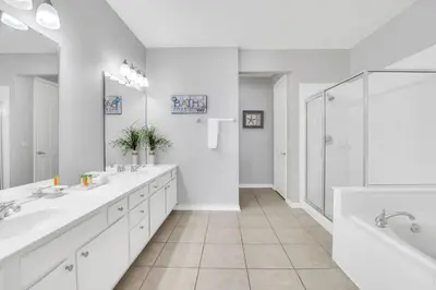 a white bathroom with two sinks and a shower at Lake Front Huge by clubhouse in Orlando