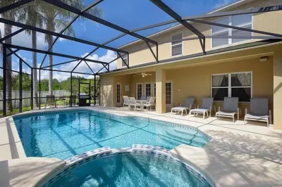 a swimming pool with chairs and a house at Enchanted Villa Oasis in Orlando