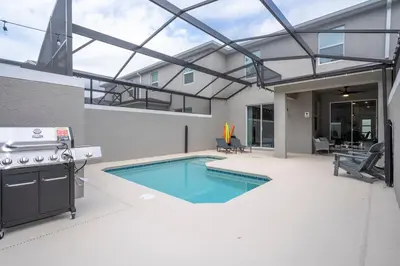 a swimming pool in the middle of a patio with a stove at Amazing Disney resort style & FREE Waterpark 2481 in Kissimmee