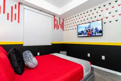 a bedroom with a red bed and a flat screen tv at 3BR Resort Condo FREE Waterpark 3150 in Kissimmee