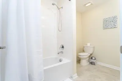 a white bathroom with a toilet and a shower at 3BR Resort Condo FREE Waterpark 3150 in Kissimmee