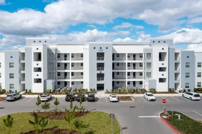 a large white building with cars parked in a parking lot at 3BR Resort Condo FREE Waterpark 3150 in Kissimmee
