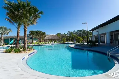 a large swimming pool with palm trees and a building at Lake view & Free Resort Access near Disney 4399 in Kissimmee