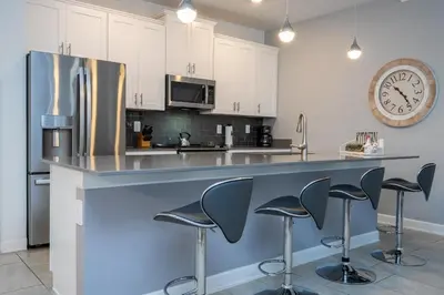 a kitchen with a counter with stools and a clock at Cozy home Near Disney Free resort Access 4463 in Kissimmee