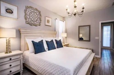 a bedroom with a bed with blue pillows and a chandelier at Gorgeous Vacation Home near Everywhere in Kissimmee