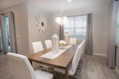 a dining room table with white chairs and a vase at Gorgeous Vacation Home near Everywhere in Kissimmee