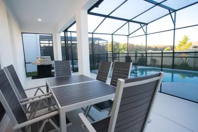 a patio with a table and chairs and a pool at Gorgeous Vacation Home near Everywhere in Kissimmee