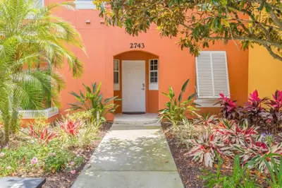 a orange building with a white door and plants at Townhome at Emerald Island Resort in Kissimmee