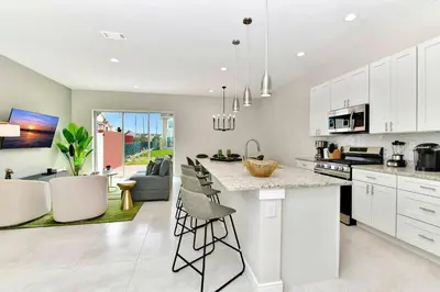 a kitchen with white cabinets and a kitchen island with bar stools at New Towhouse 2025 in Orlando