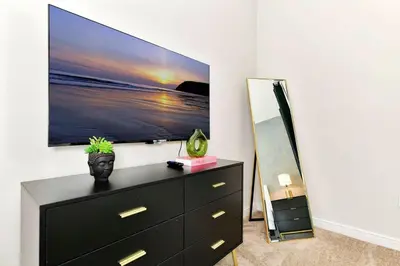 a bedroom with a dresser with a tv on the wall at New Towhouse 2025 in Orlando