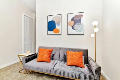 a living room with a gray couch with orange pillows at New Towhouse 2025 in Orlando