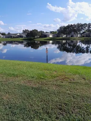 a pond with a sign in the middle of a field at Three-Bedroom House in Clear Creek in Orlando