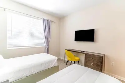 a bedroom with two beds and a desk with a television at Apartment at Vista Cay Resort in Orlando