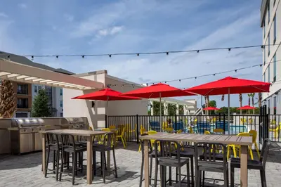 a patio with tables and chairs with red umbrellas at Home2 Suites By Hilton Lake Mary Orlando in Lake Mary