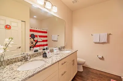 a bathroom with a sink and a toilet and a mirror at New in the market townhouse in West Lucaya! in Kissimmee