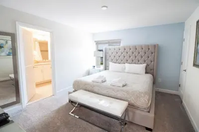 a white bedroom with a large bed and a stool at Private Pool Townhome at Storey Lake Resort in Kissimmee