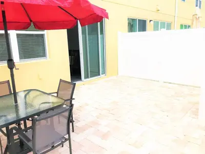 a table with a red umbrella on a patio at Townhome at Compass Bay Community in Kissimmee