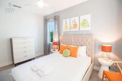 a bedroom with a white bed with orange pillows at Private Pool and Spa Home at Encore Resort at Reunion in Orlando