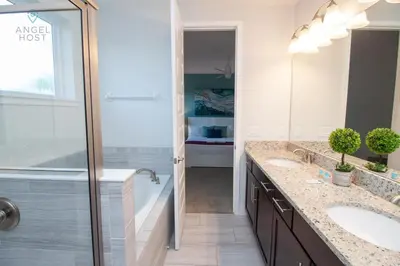 a white bathroom with two sinks and a shower at Private Pool and Spa Home at Encore Resort at Reunion in Orlando