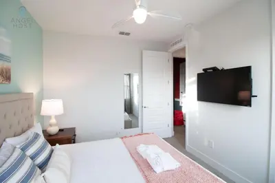 a white bedroom with a bed and a flat screen tv at Private Pool and Spa Home at Encore Resort at Reunion in Orlando