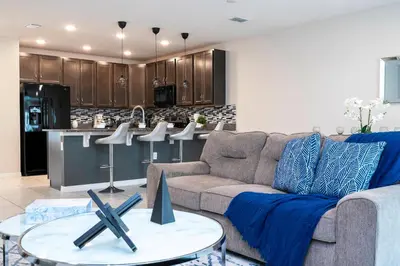 a living room with a couch and a kitchen at Amazing 3BedroomsNear to DisneyThemed rooms in Kissimmee