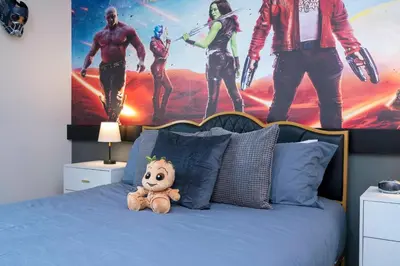 a teddy bear sitting on a bed with a marvel mural at Amazing 3BedroomsNear to DisneyThemed rooms in Kissimmee