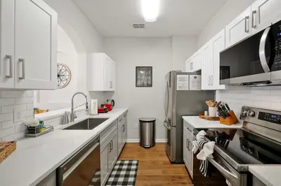 a kitchen with white cabinets and a stainless steel refrigerator at Sunny Condo Retreat at Windsor Hills in Orlando